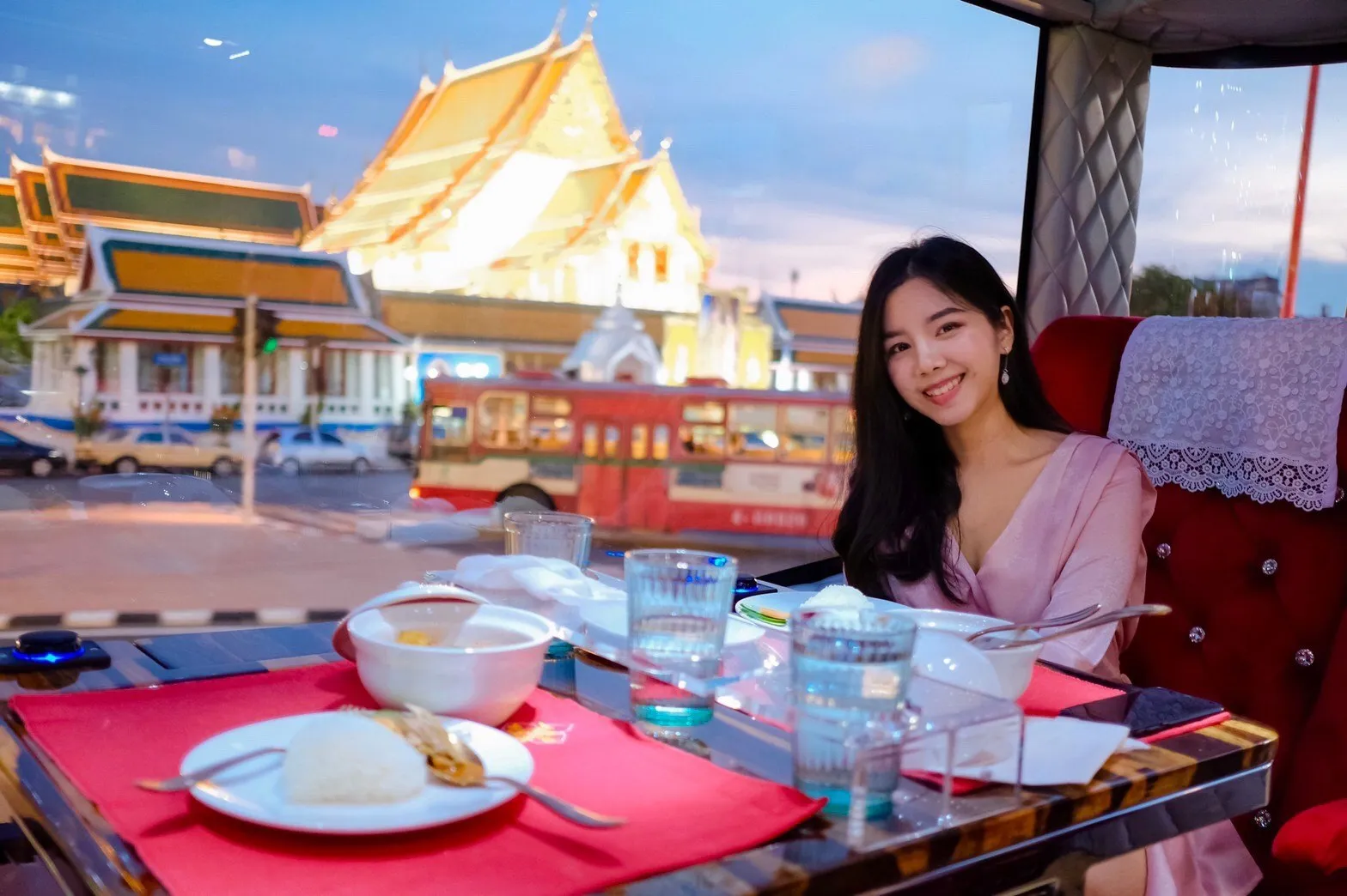 Guest dining inside the bus with ornate Thai temple and golden spires in background