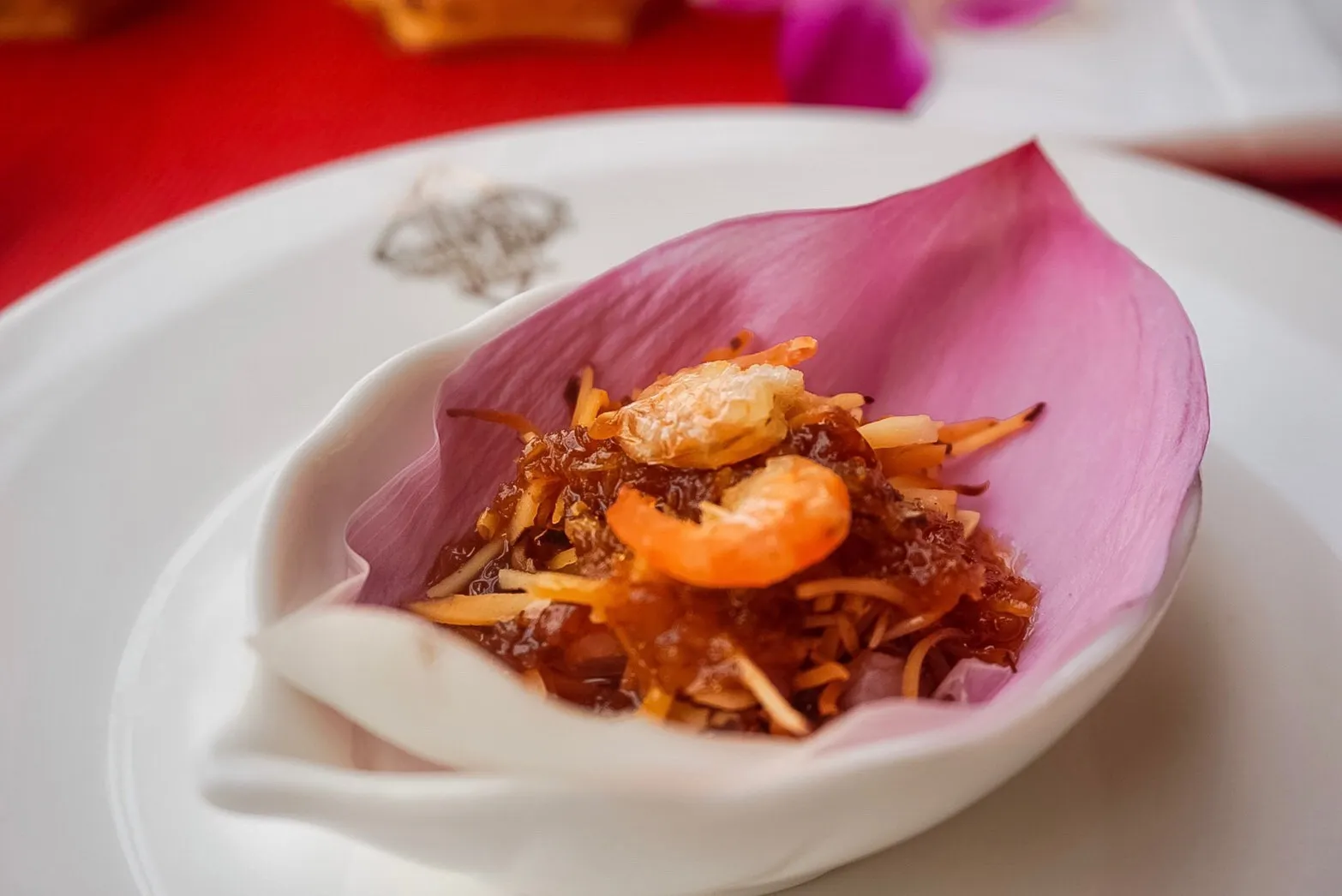 Close-up of prepared crab dish on pink shell-shaped plate with fresh garnish