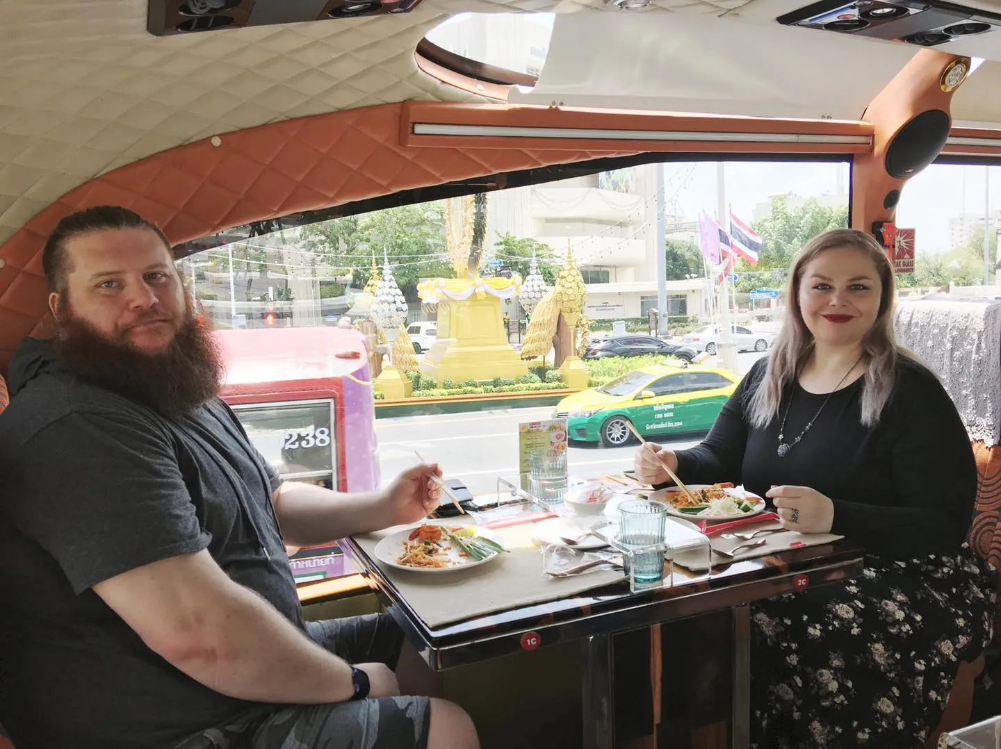 Two male guests dining with large window view of Bangkok street and colorful buildings