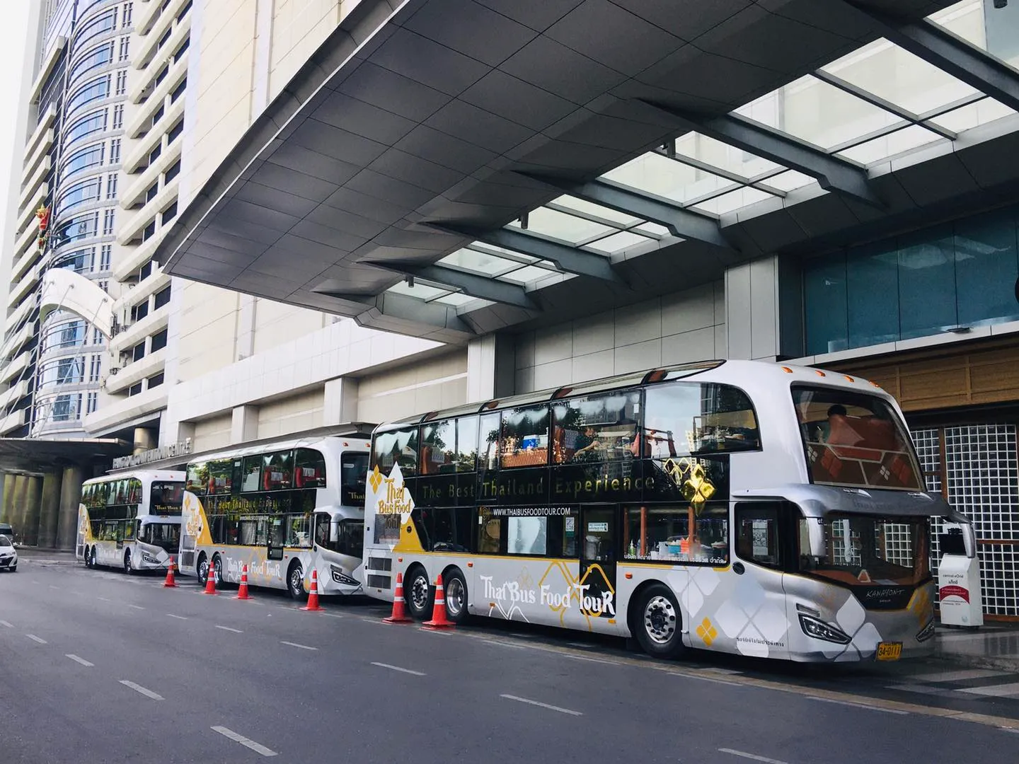 Team members in Thai Bus Food Tour uniforms making traditional Thai wai greeting gesture