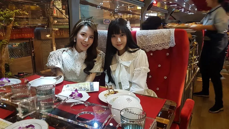 Two elegantly dressed female guests dining inside bus with jewelry visible and formal setting