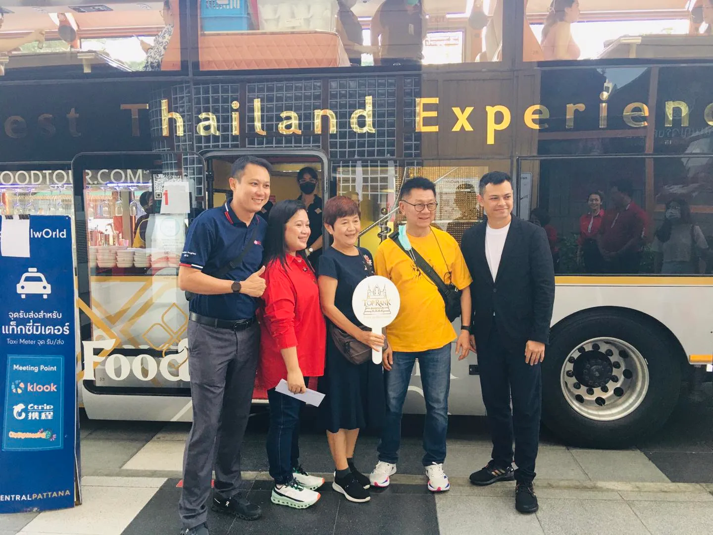 Mixed group of guests dining inside bus during evening with colorful city lights reflecting