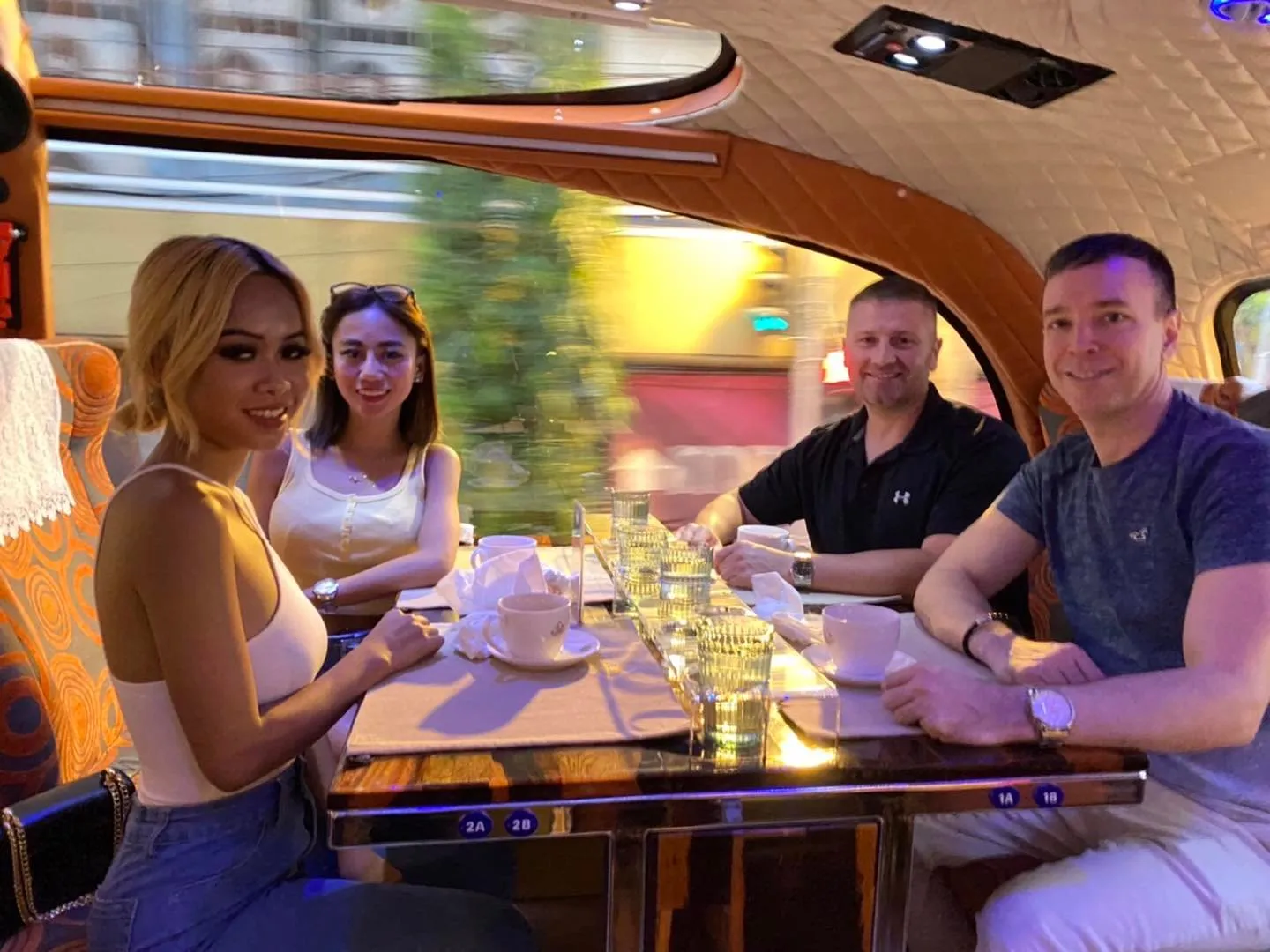 Two male guests in business casual attire giving thumbs up while dining inside bus