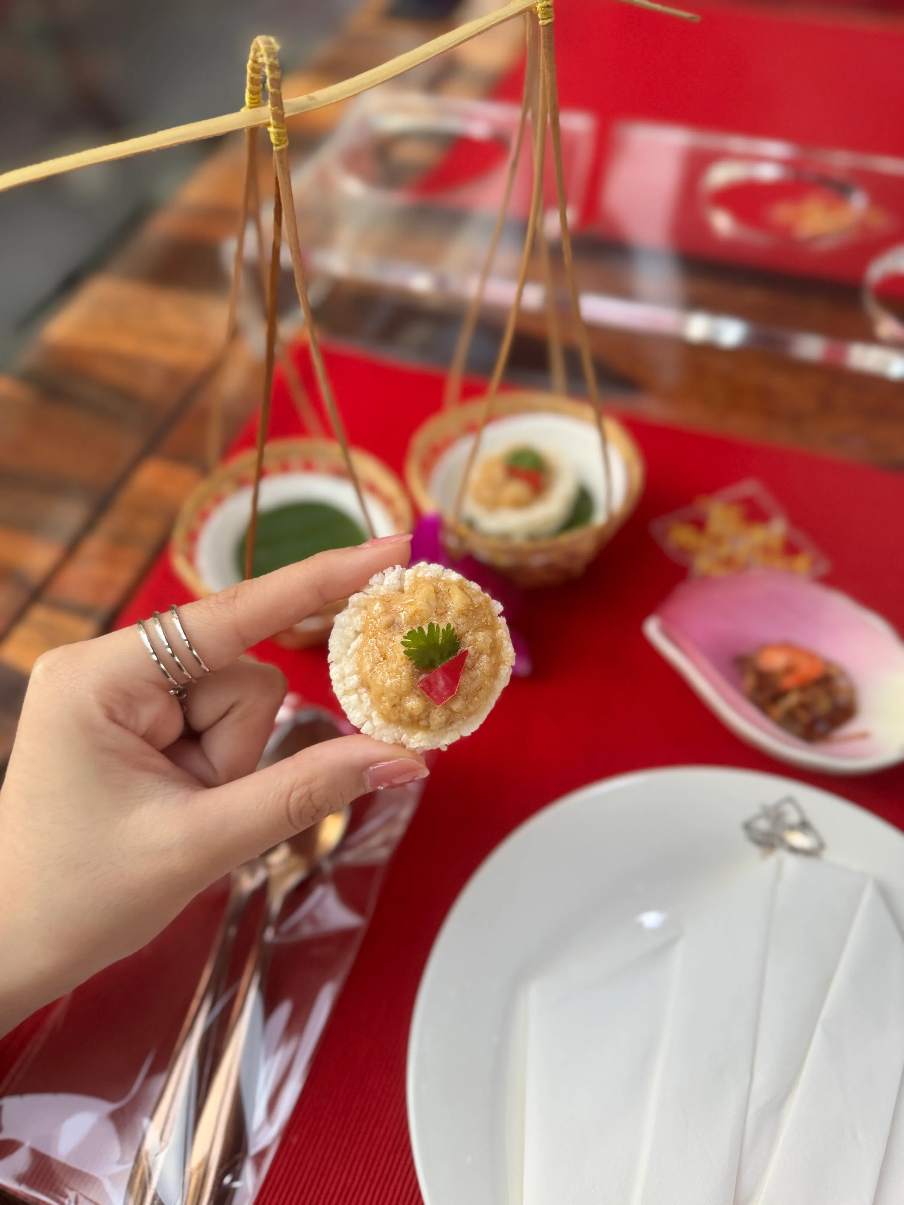 Hanging baskets with Thai appetizers and close-up of sticky mango rice with purple orchid