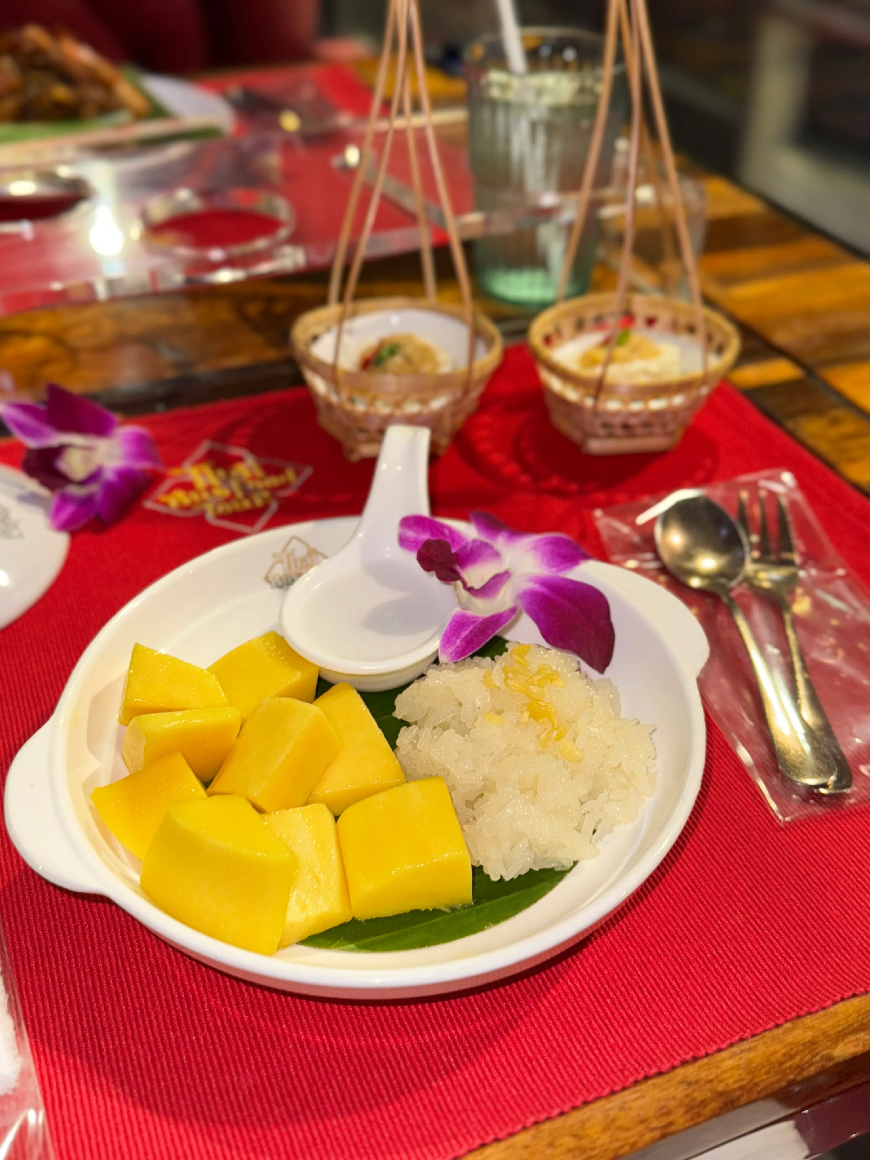 White cup of black coffee with purple orchid flower on red table setting inside bus