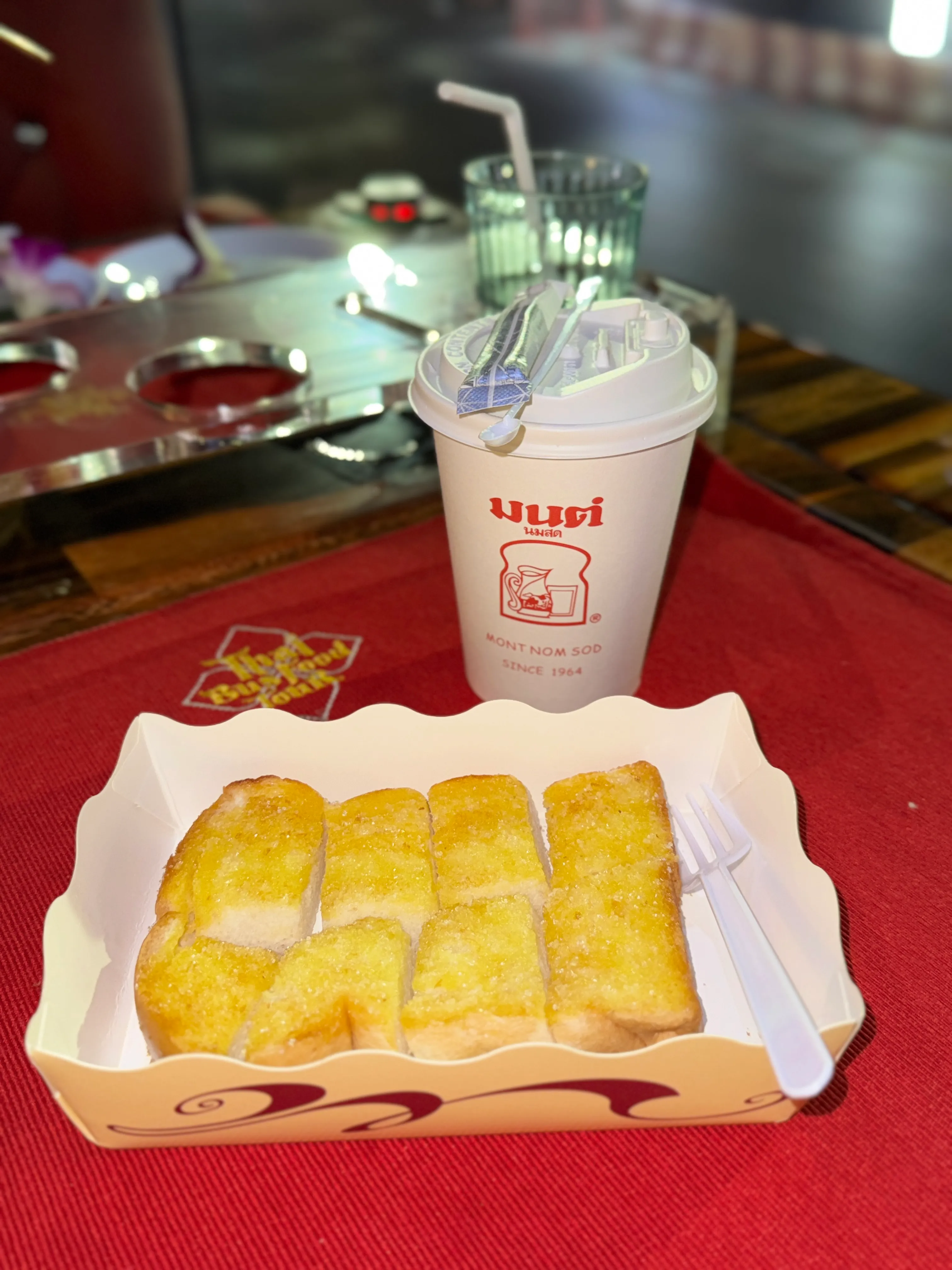 Close-up of hand holding dessert cup during tour with blurred background and decorative items