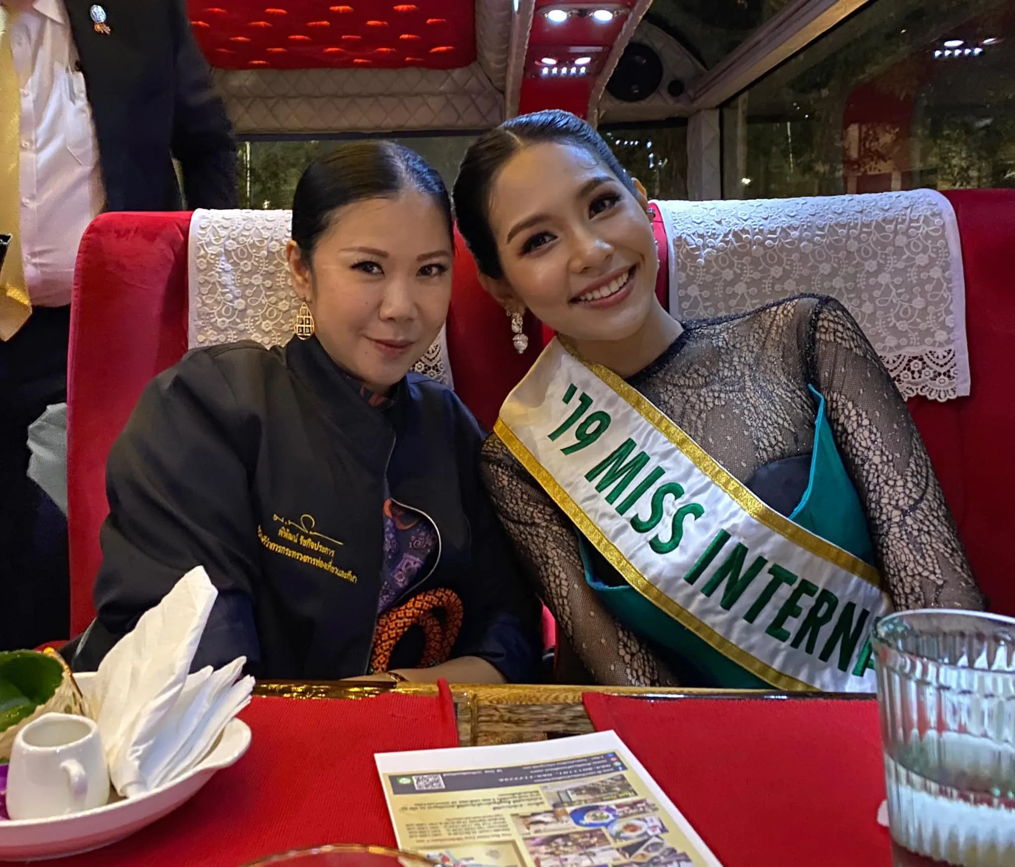 Two female guests in elegant attire laughing while enjoying wrapped sticky rice dessert