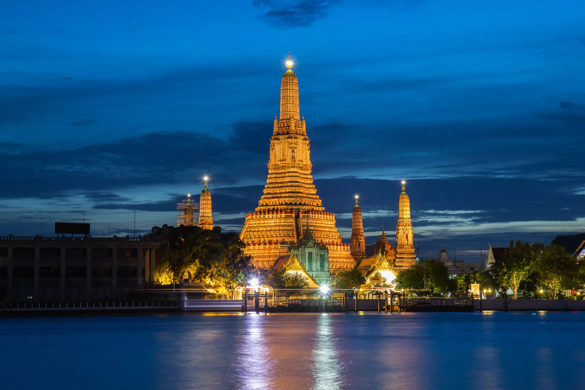 Wat Arun the Temple of Dawn illuminated at night, its central prang reflected in the Chao Phraya River