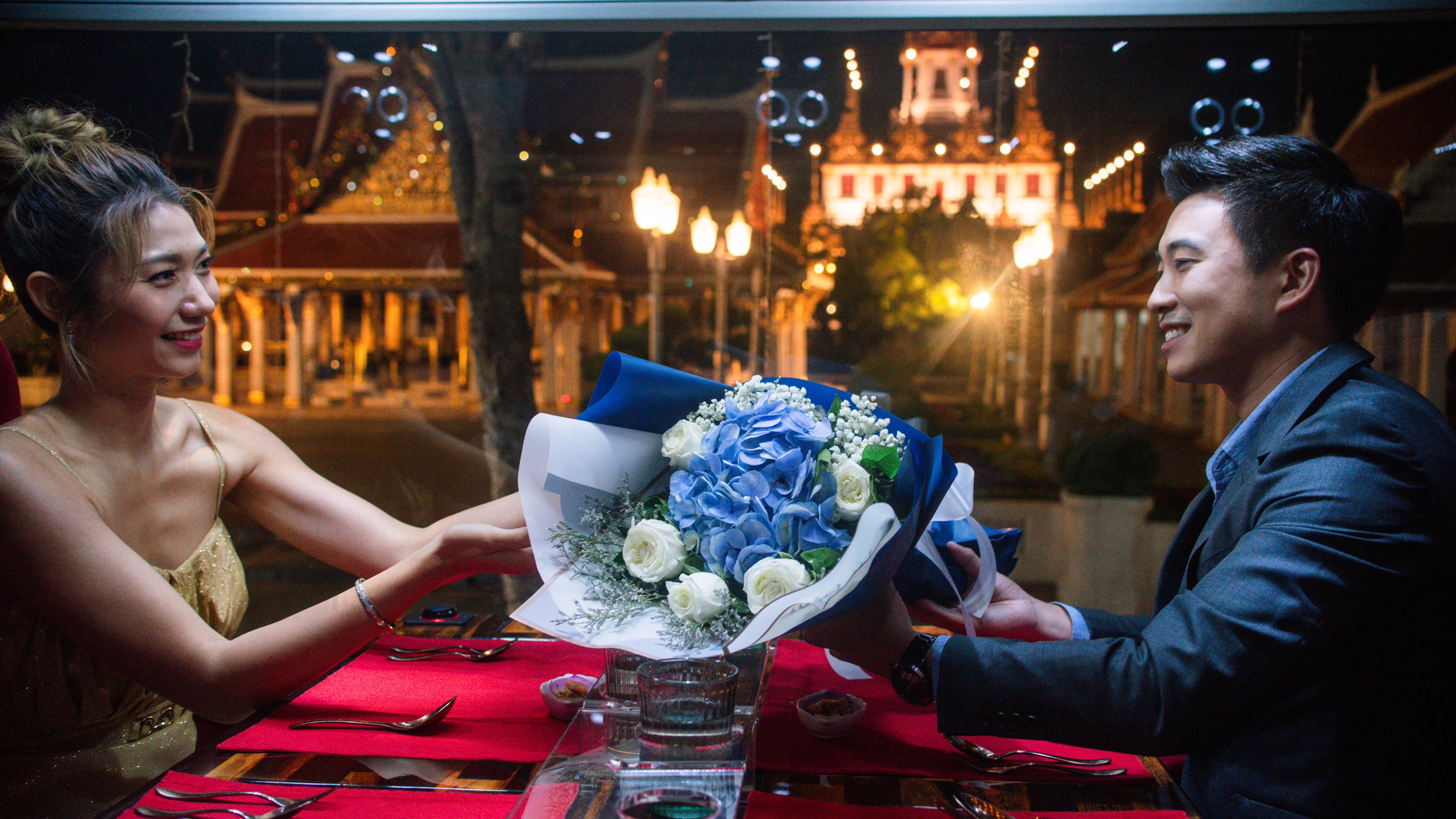 Illuminated Wat Arun and Bangkok city lights at night seen through the panoramic window of the Thai Bus Food Tour double-decker dining bus