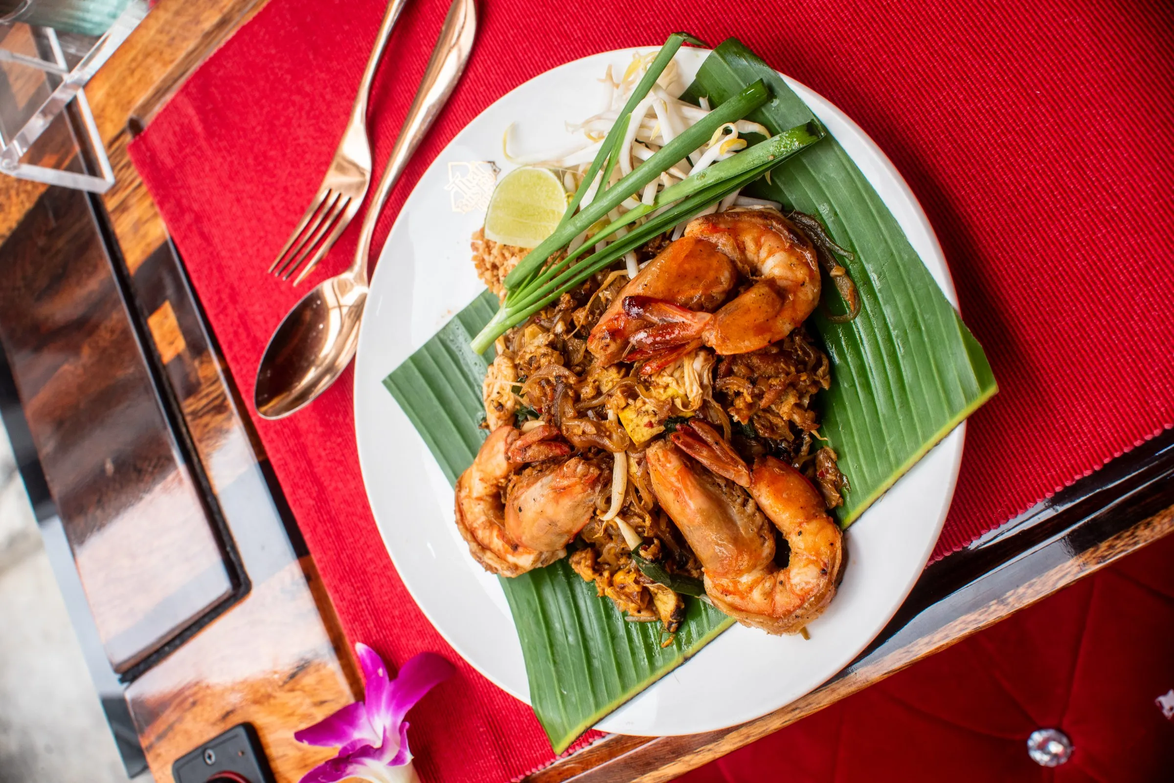 Close-up of wok-fired Pad Thai Fai Ta Lu served at a window table on the Thai Bus Food Tour, with the Grand Palace visible through the panoramic glass