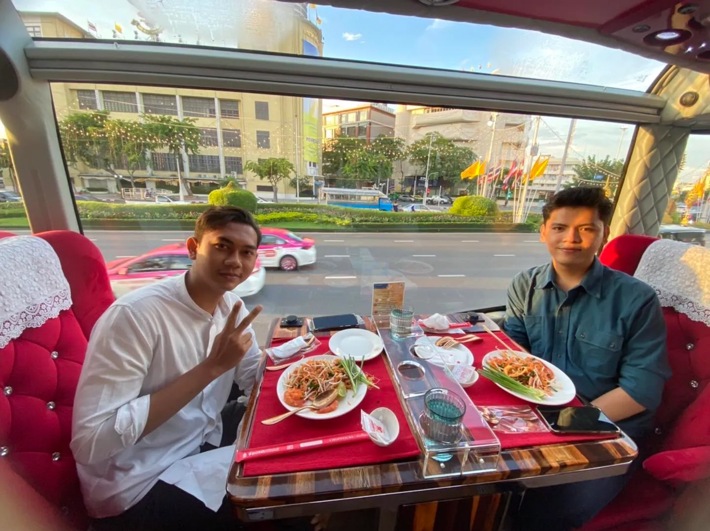 Guests dining in cool air-conditioned comfort while sunny Bangkok streets pass the panoramic window